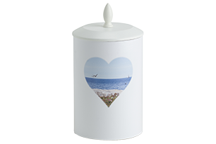 Vit burk med lock och hjärtformat strandmotiv.