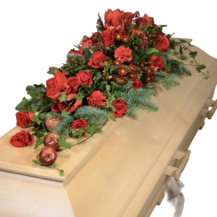 Kista dekorerad med ett blomsterarrangemang av röda rosor och gröna blad.